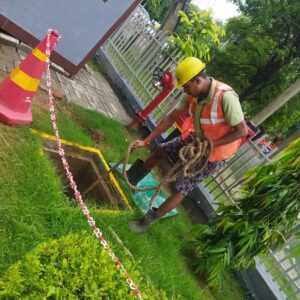 NIPSTec's worker performing maintenance of rainwater harvesting pit on site.